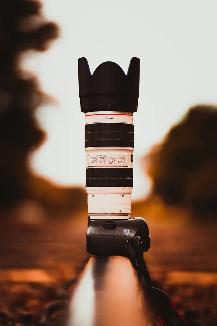 Stylish telephoto lens on DSLR camera placed outdoors with blurred bokeh background.
